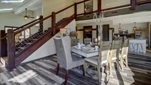 A spacious dining area with a high ceiling, a staircase with wooden railings, and a chandelier. - Emmas Rare Find by Beyond Expectations Cabin With Hot Tub (Sevierville)