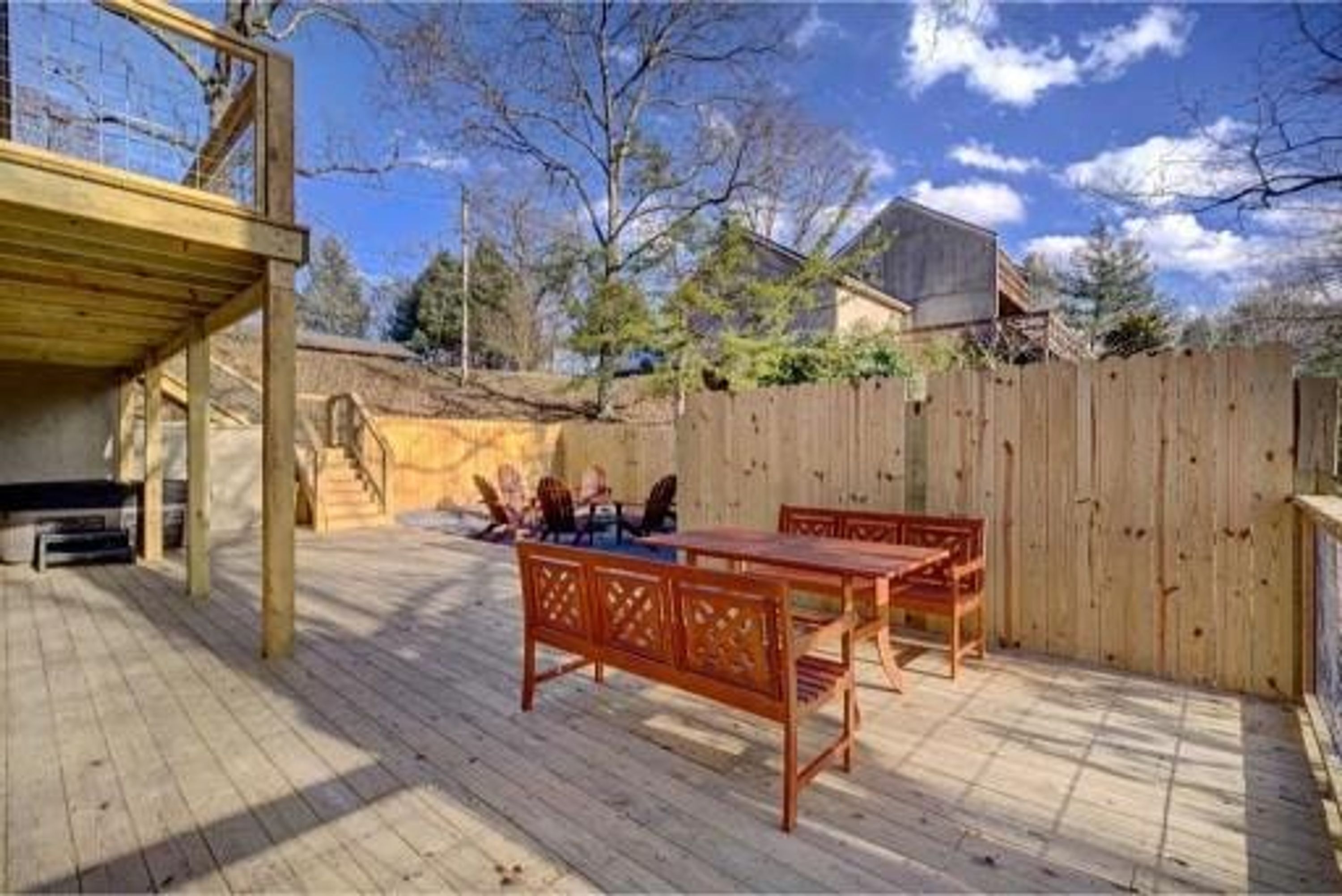 A wooden deck with a table and chairs, a covered area, and a wooden fence.