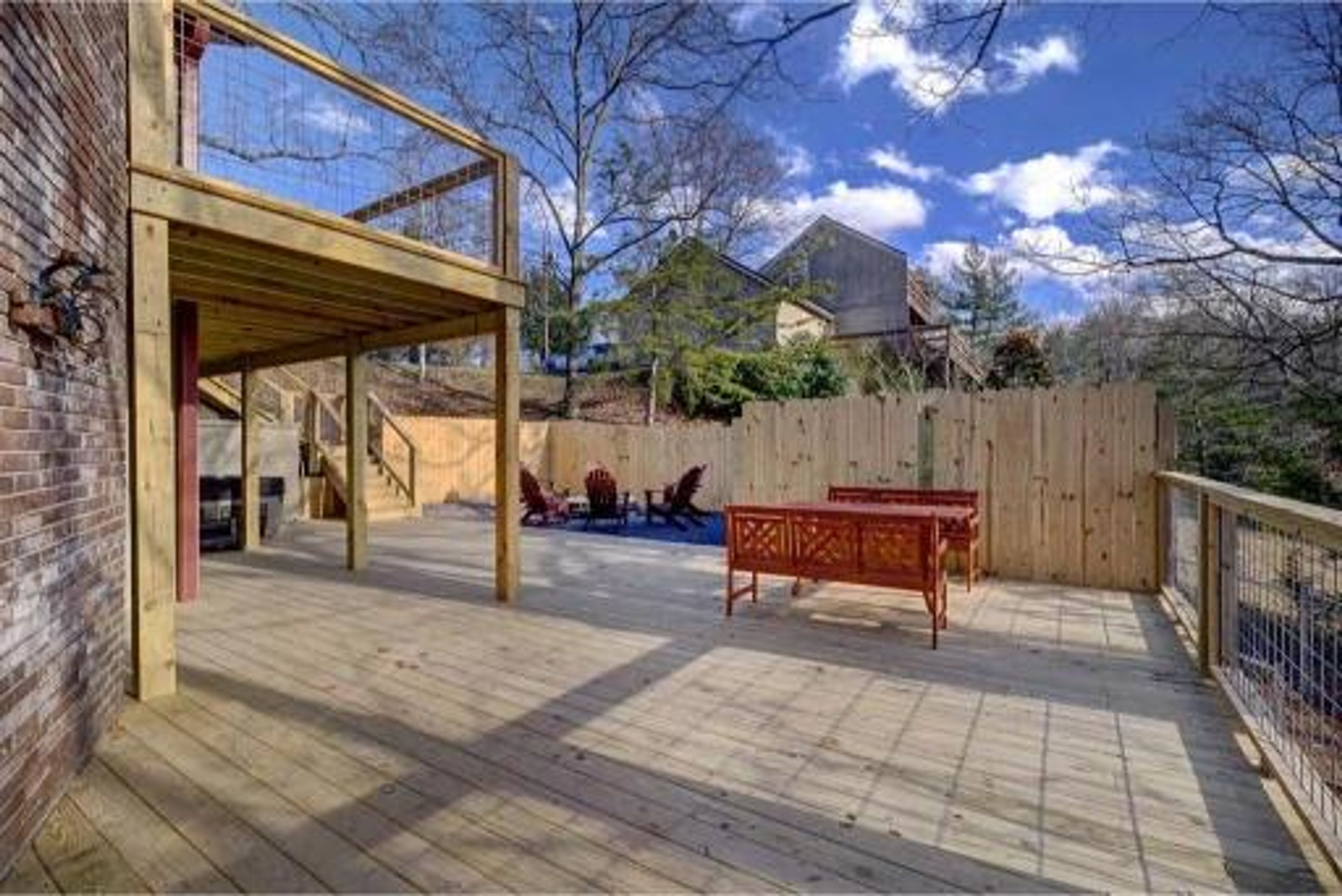 Une terrasse en bois avec un espace abrité, une table rouge et un mur en briques.