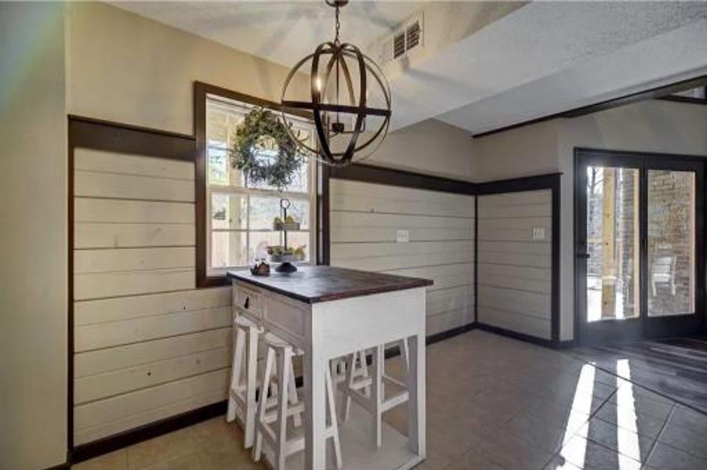 A kitchen with a central island, a hanging light fixture, and a window with a view.