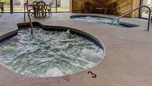 A spa area with two hot tubs, wooden walls, and a seating area with chairs. - Stone Crest Summit by Beyond Expectations With Pool (Gatlinburg)