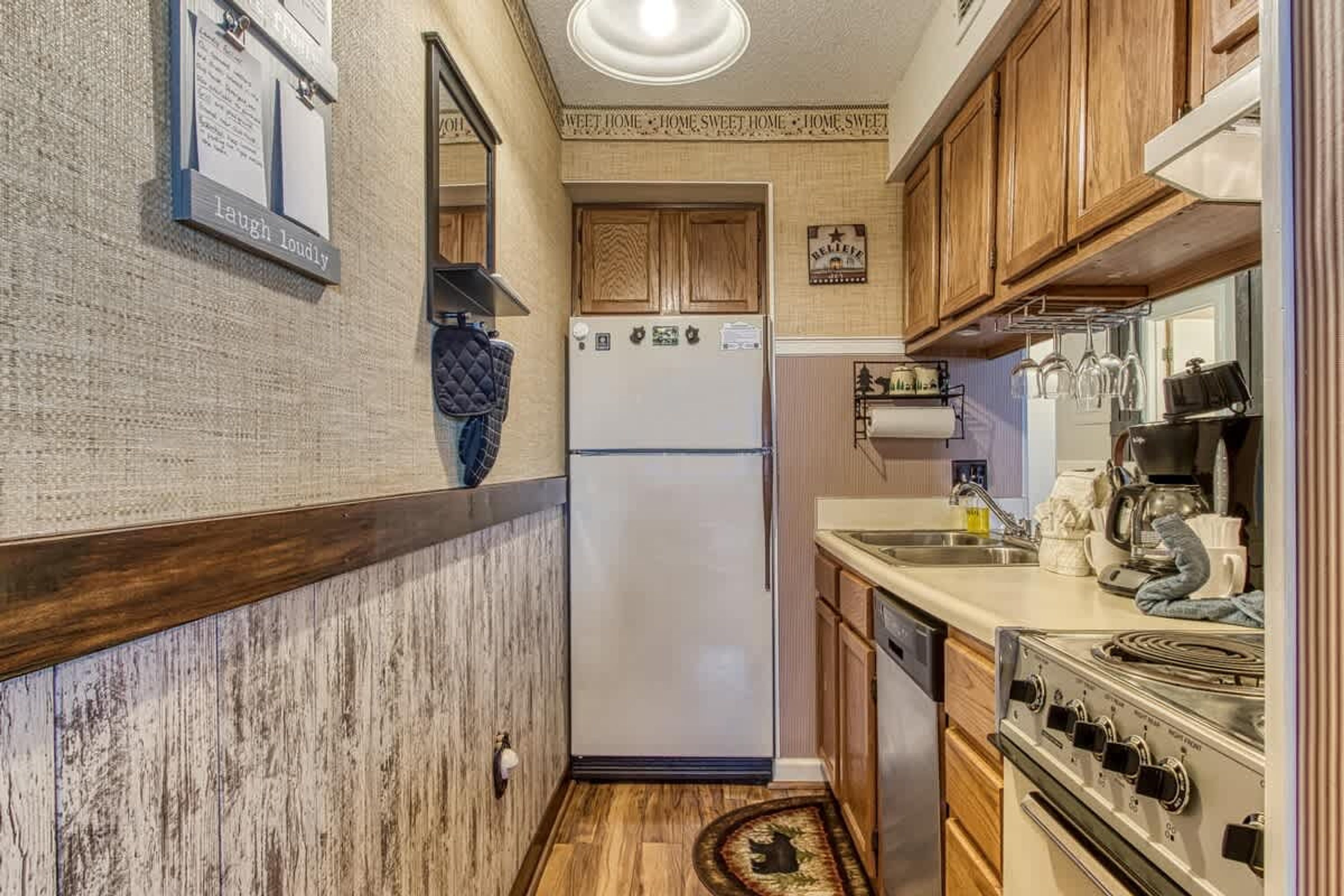 A compact kitchen with a refrigerator, stove, and wooden cabinets.