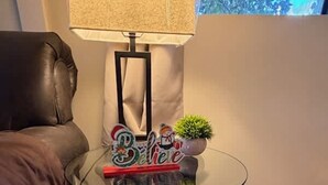 Una mesa con cubierta de vidrio, una figurita de oso, una planta pequeña y un letrero que dice 'Believe'.