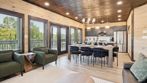 Une cuisine moderne avec un coin repas, un plafond en bois et de grandes fenêtres.