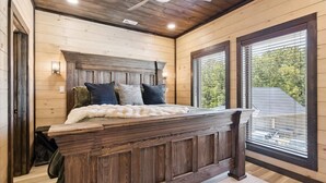 Une chambre à coucher avec une tête de lit en bois, un grand lit et une vue par la fenêtre.