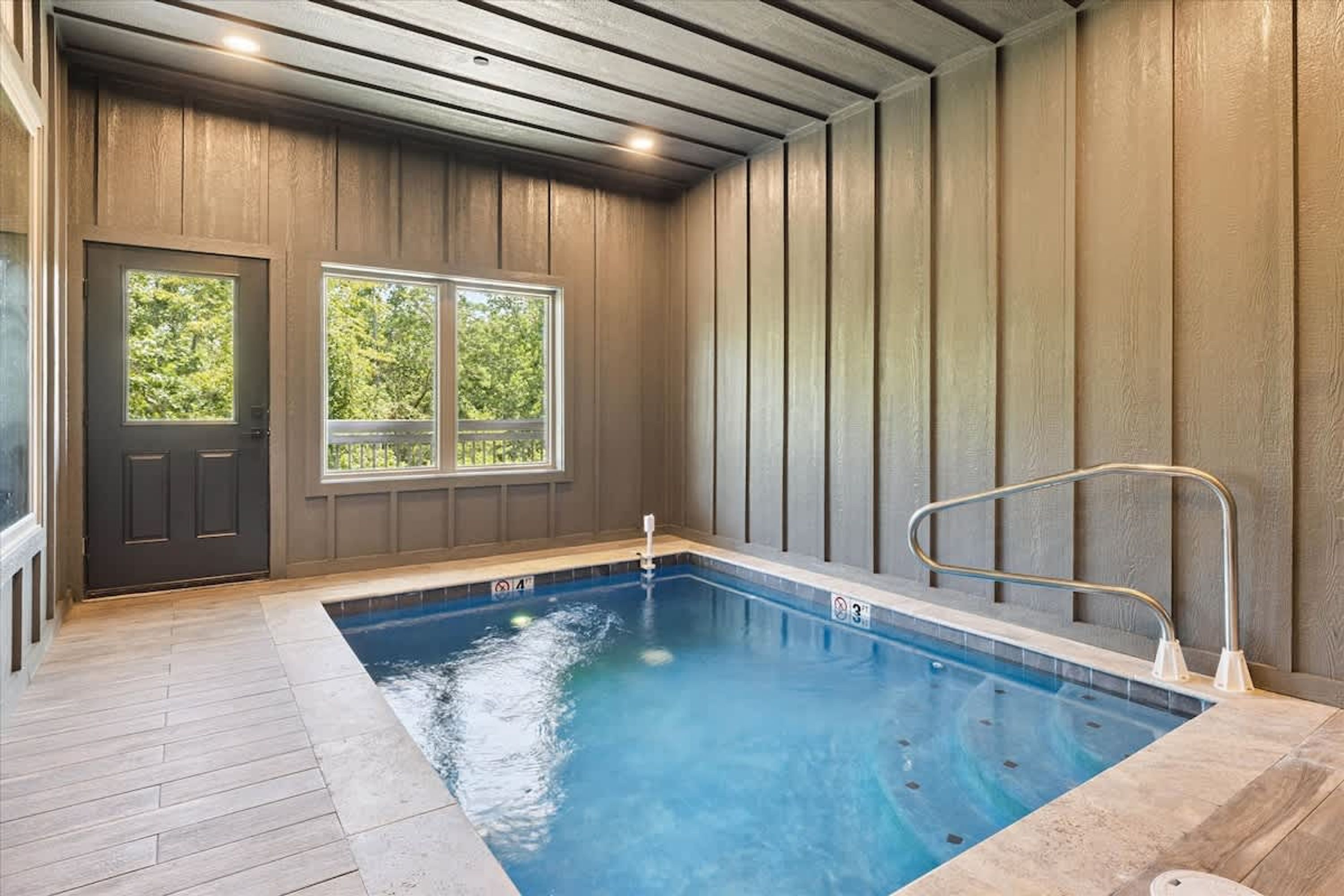An indoor swimming pool with wooden walls and a door with windows.