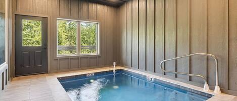 An indoor swimming pool with wooden walls and a door with windows.