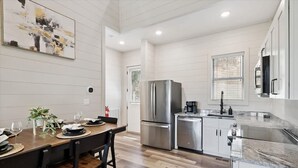A modern kitchen with a stainless steel refrigerator, a coffee maker, and a dining area with a wooden table and chairs. - Smoky Shores Lakeview Cabin by Beyond Expectations (Sevierville)