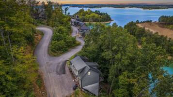 A secluded cabin with a winding road, surrounded by dense forest and a lake.