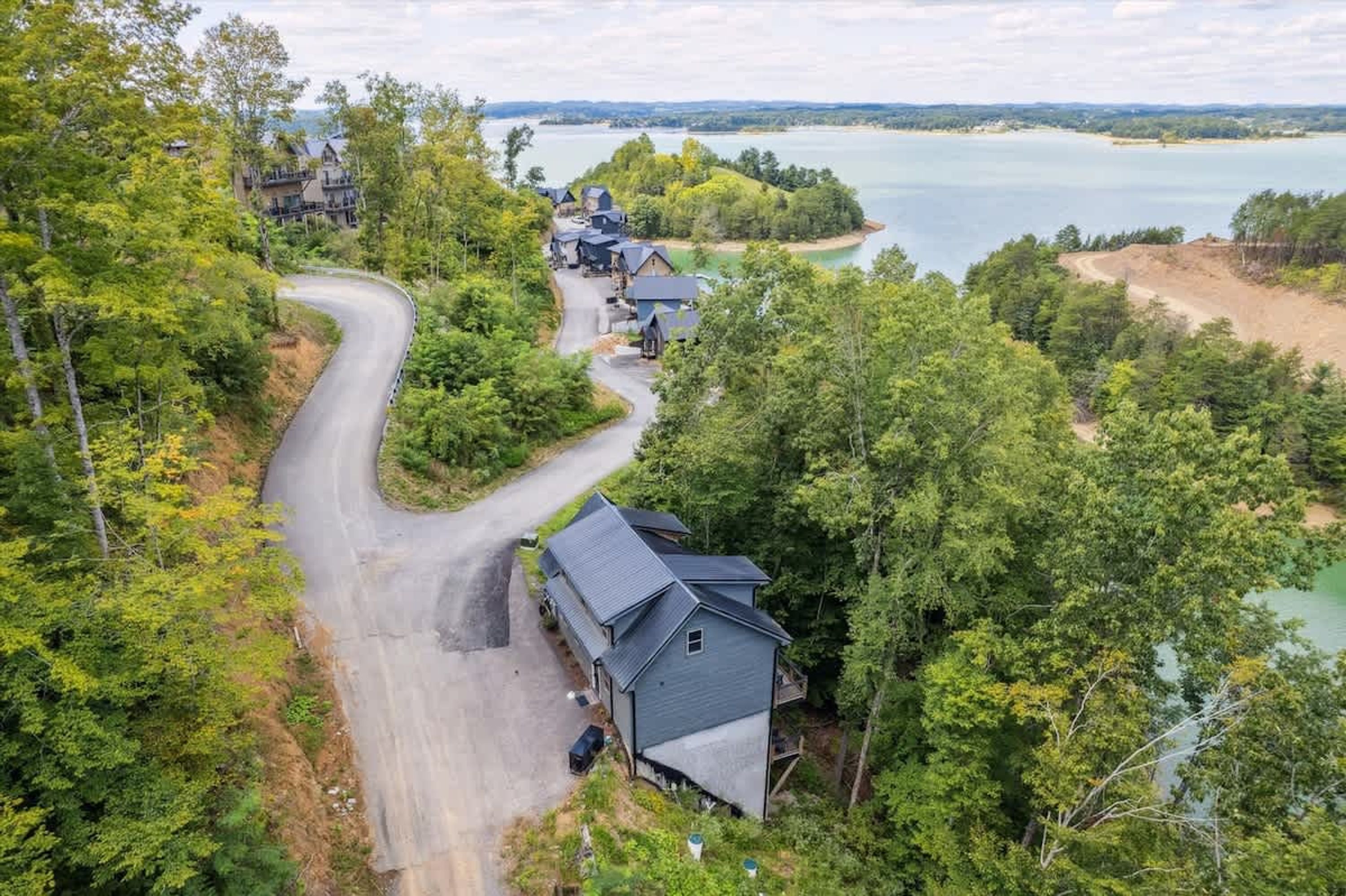 Un barrio residencial con casas, una carretera sinuosa y un lago.