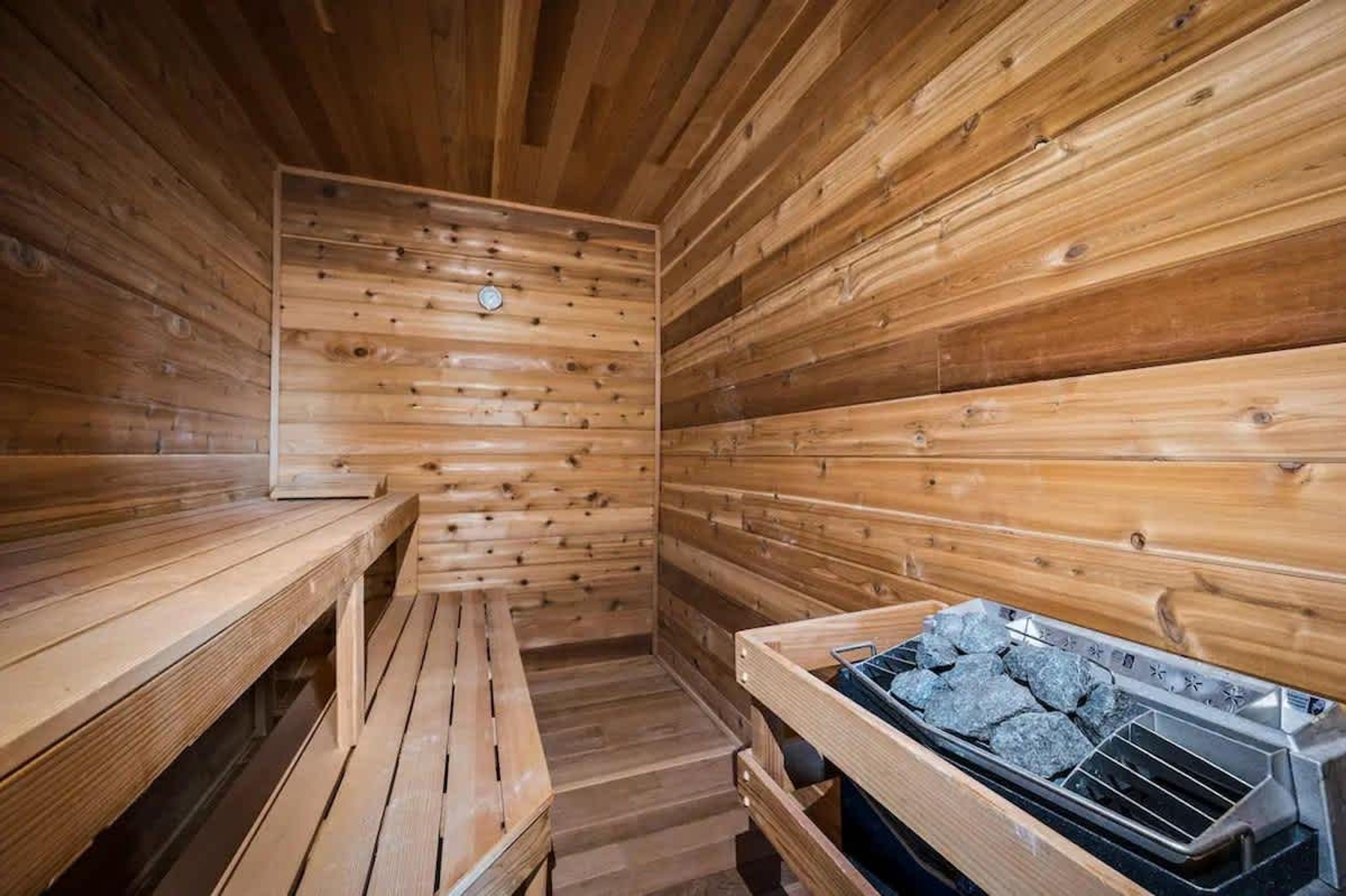 A wooden sauna with benches and a stone heating element.