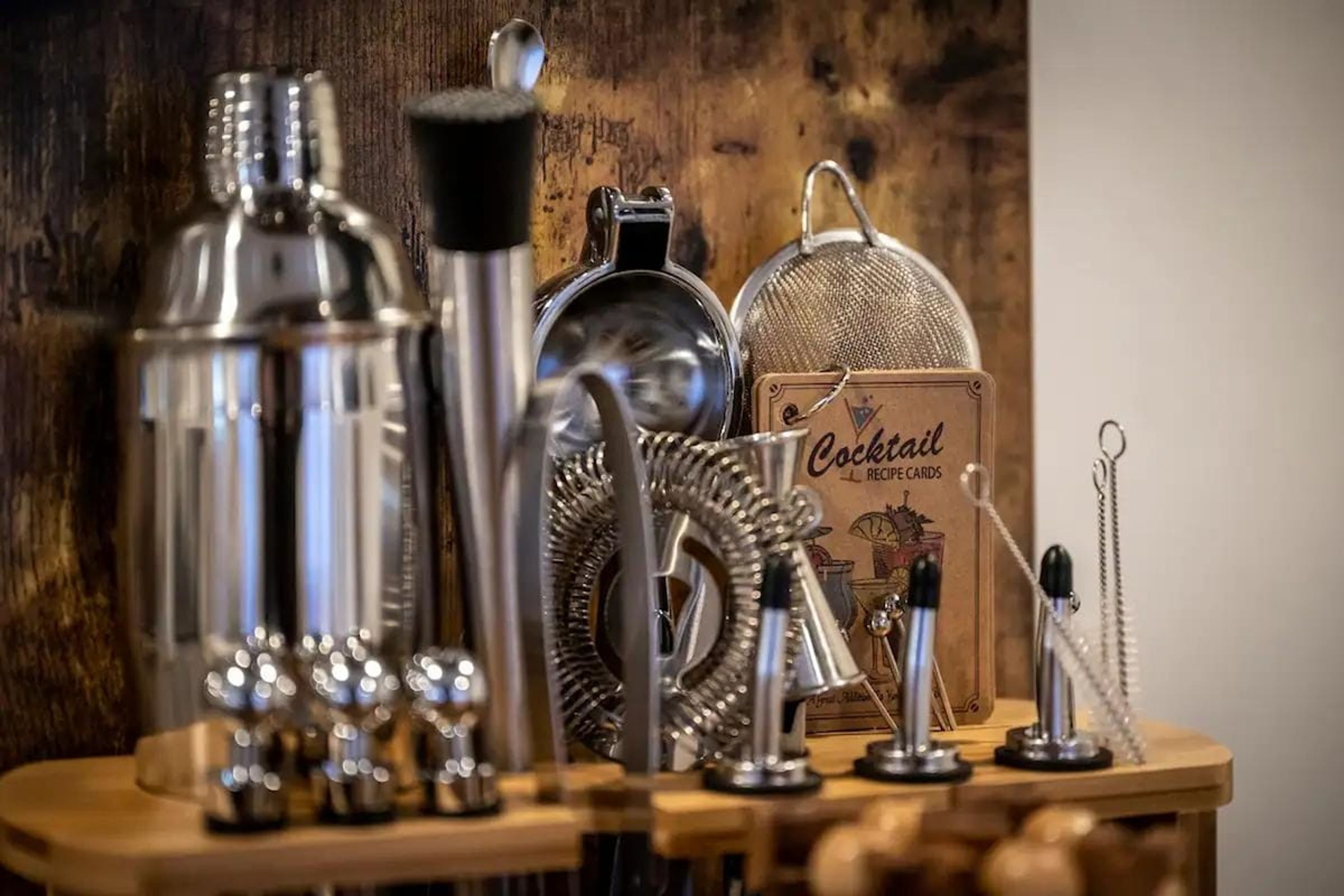 Une collection d’ustensiles pour préparer des cocktails et une carte de recettes, le tout posé sur une surface en bois.
