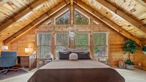 A bedroom with a sloped ceiling, a bed, a desk, and a chair. - Round Top Way Cabin by Beyond Expectations (Sevierville)