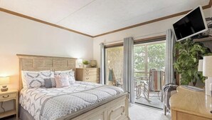 A bedroom with a bed, bedside tables, a TV, a window, and a view of the outdoors. - Misty Mountain Condo by Beyond Expectations With Hot Tub (Gatlinburg)