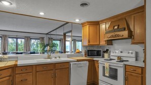 A kitchen with wooden cabinets, a microwave, stove, and a dishwasher. - Misty Mountain Condo by Beyond Expectations With Hot Tub (Gatlinburg)
