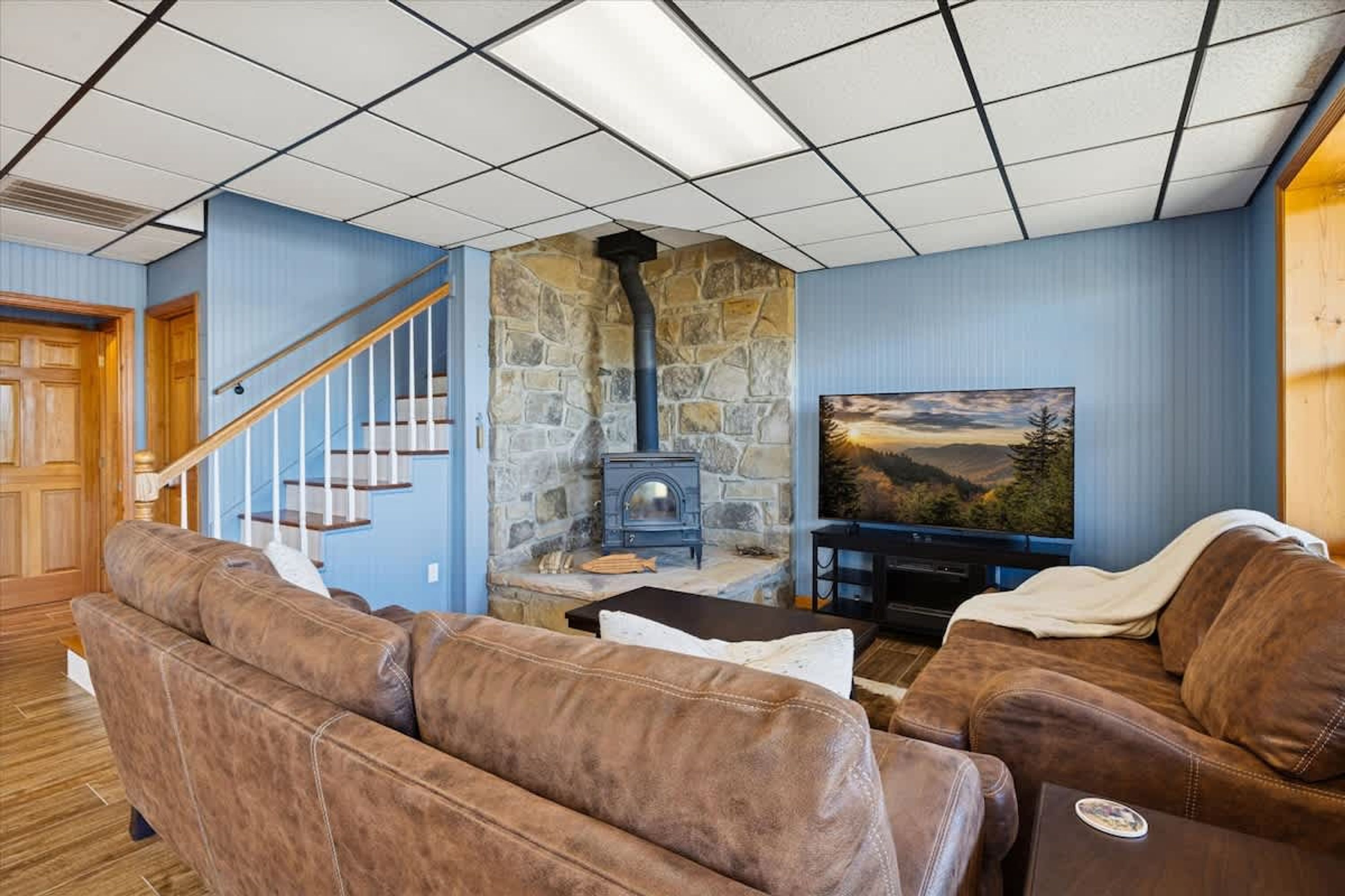 Ein Wohnzimmer mit Kamin aus Stein, einem Fernseher und Ledersofas.