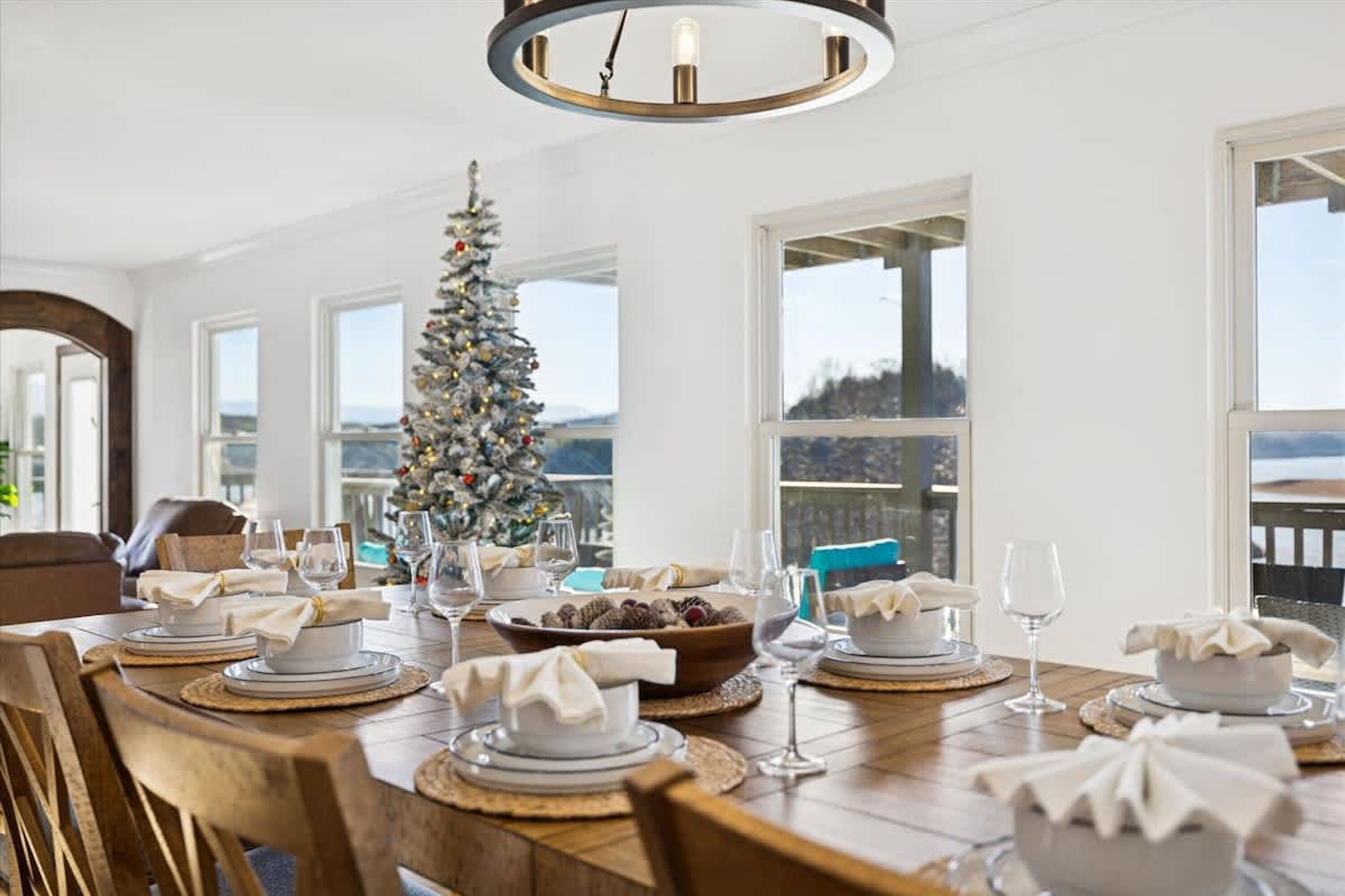 A dining area with a Christmas tree, a large window, and a view of the outdoors.