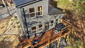 Una casa de dos pisos con un balcón, un espacio de estar al aire libre cubierto y un ventanal grande.