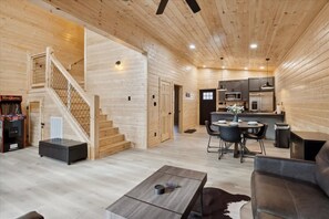 A wooden interior with a staircase, a dining area, and a kitchen. - Black Bear Cabin by Beyond Expectations With Hot Tub (Sevierville)
