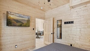 Una habitación con paneles de madera, una cama, una puerta y un cuadro colgado en la pared.