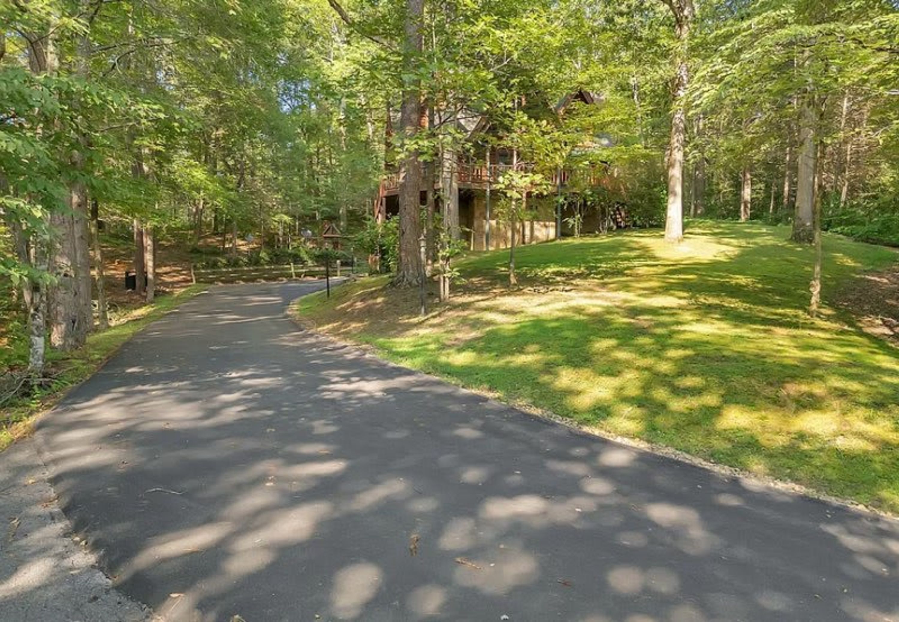 A paved driveway leading to a building surrounded by trees.