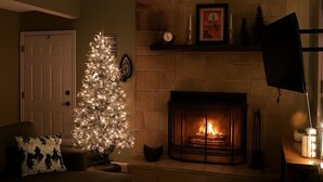 Una sala de estar acogedora con chimenea, un árbol de Navidad y una puerta.