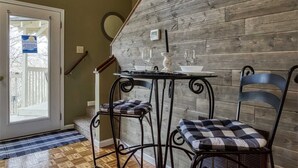 Una pared de madera, una mesa con sillas, una puerta y un felpudo.