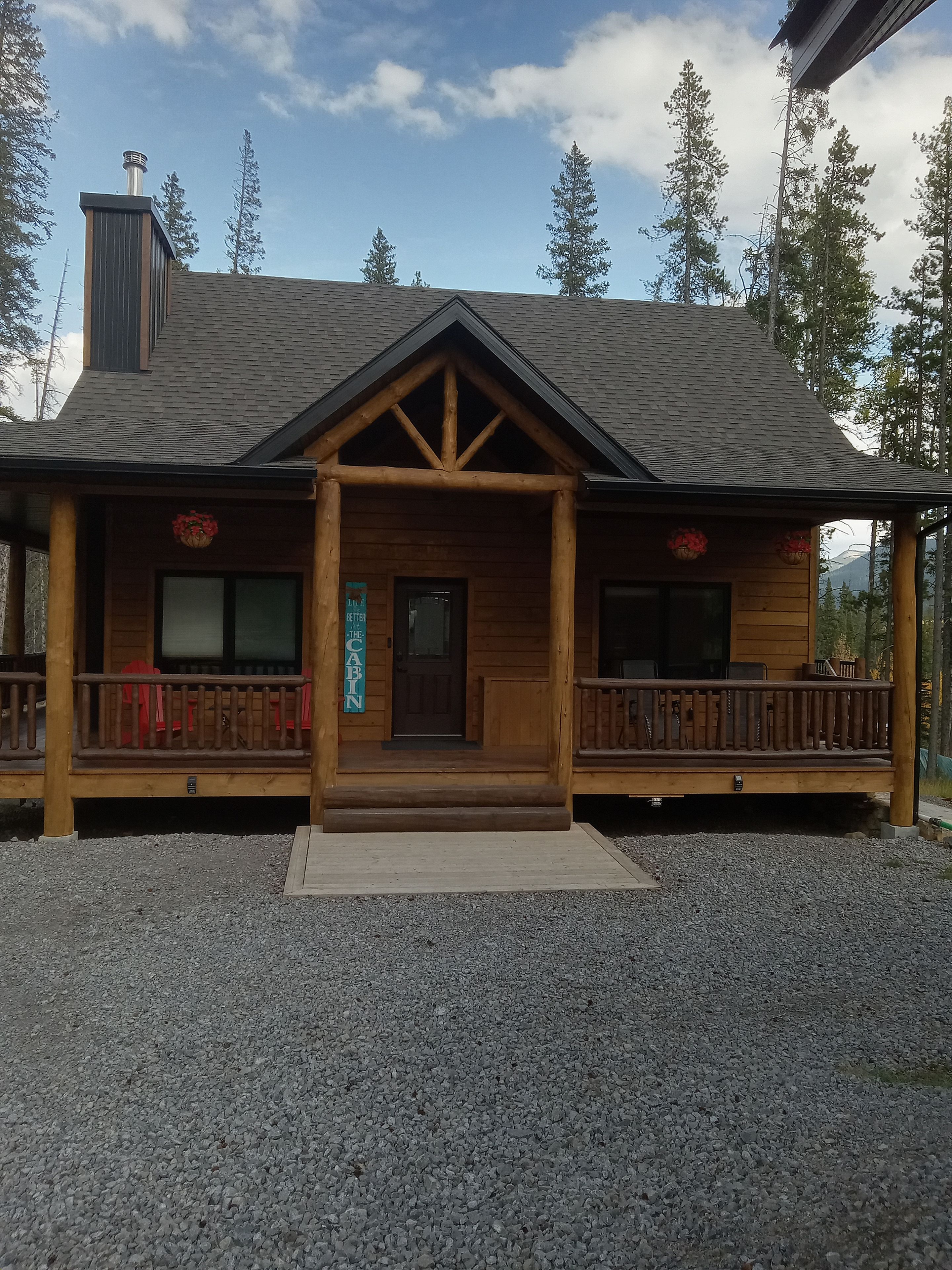 Une cabane en bois avec un porche, une cheminée et une enseigne indiquant qu’il s’agit d’une cabane.