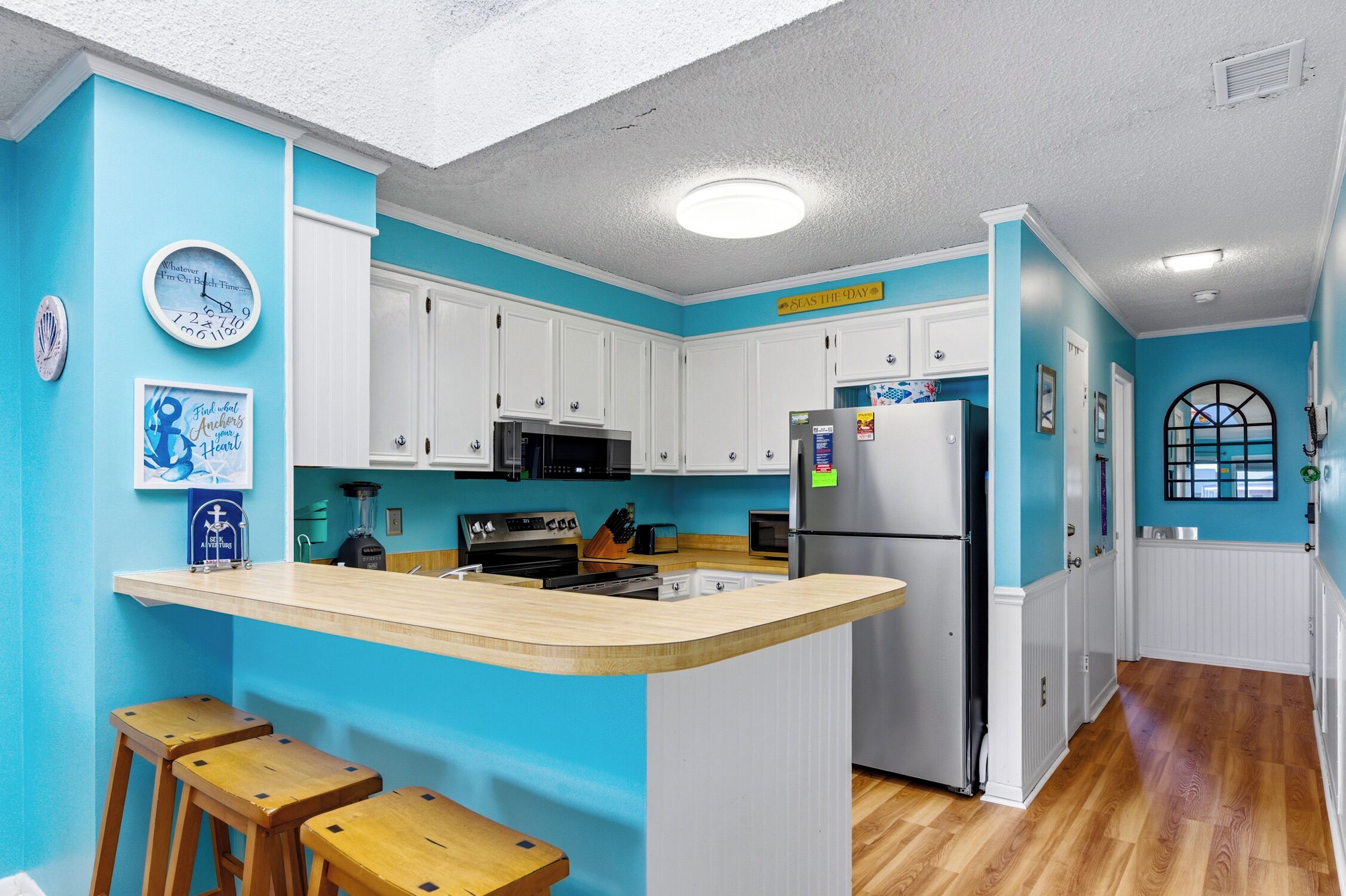 Una cocina con armarios blancos, encimera de madera y un reloj en la pared.