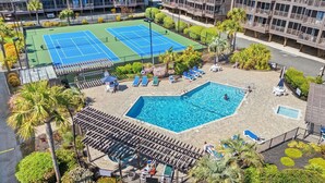 Un espace piscine aménagé sur le toit, comprenant un court de tennis, des chaises longues et une petite piscine.