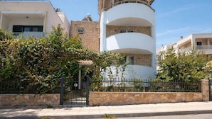 Ein modernes Gebäude mit einer Stein-Fassade, einem weißen Balkon und einem verschlossenen Eingang.