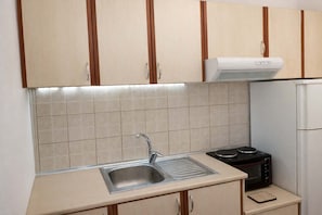 Une cuisine avec des armoires de couleur beige, un évier en acier inoxydable, un four à micro-ondes et un four encastré.