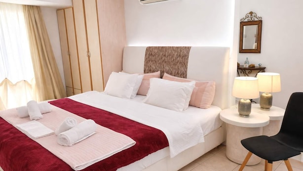 Una habitación de hotel con una cama grande, una mesita de noche con lámparas, una silla, un armario y un espejo en la pared.