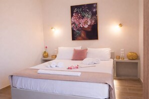 A neatly made bed with white and pink linens, a painting above it, and two bedside tables with lamps and decorative items. - Diana s House 4 - Gytheio Sandy Beach Haven (East Mani)