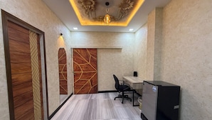A modern office space with a wooden door, a desk with a computer, and a refrigerator.