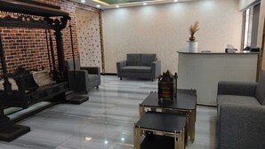 A modern living room with a brick accent wall, a sofa, armchairs, a coffee table, and a decorative fireplace.