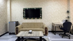 A room with a sofa, a coffee table, a TV mounted on the wall, a desk, and a chair.