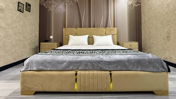 A modern bedroom with a large bed, wooden headboard, and decorative wall panels.