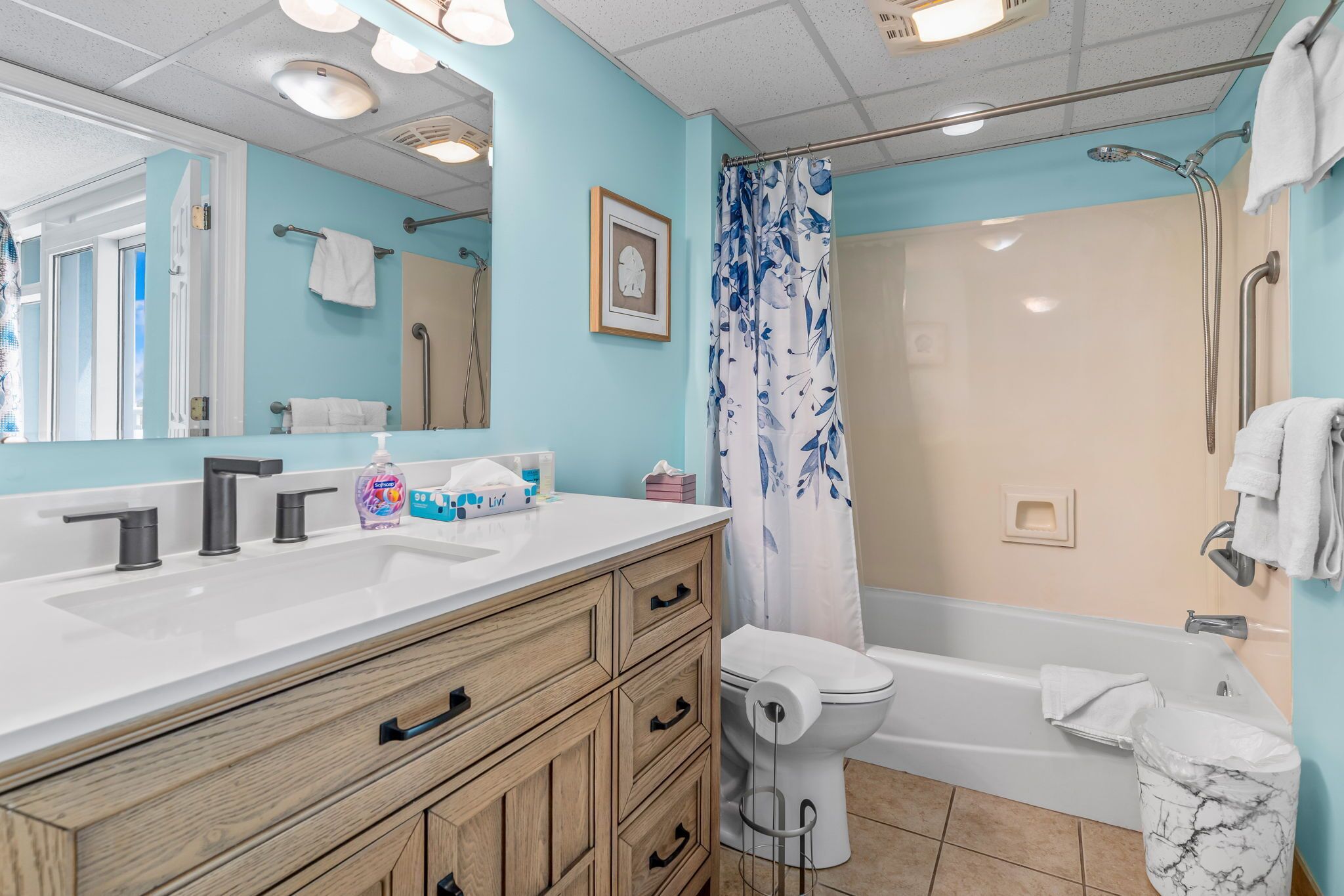 A bathroom with a white sink, wooden vanity, a toilet, and a bathtub.