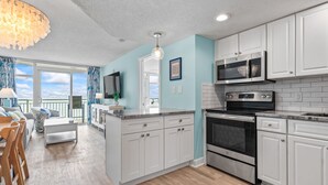 A modern kitchen with white cabinets, a stainless steel oven, and a microwave.