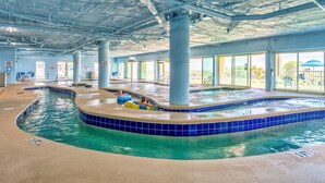 An indoor swimming pool with clear water, blue-tiled edges, and visible structural beams.
