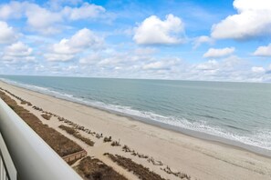 A beach view with a clear sky, sandy beach, and a wooden walkway leading to the water. - NEW Oceanfront Master 2bd/2ba Free Parking & WiFi (Myrtle Beach)
