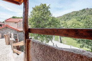 Ein Gebäude aus Stein mit roten Ziegeln, einem Holzzaun und Blick auf einen grünen Hügel.