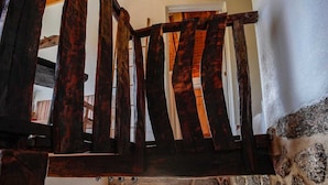Una escalera con barandillas de madera oscura y un muro de piedra.