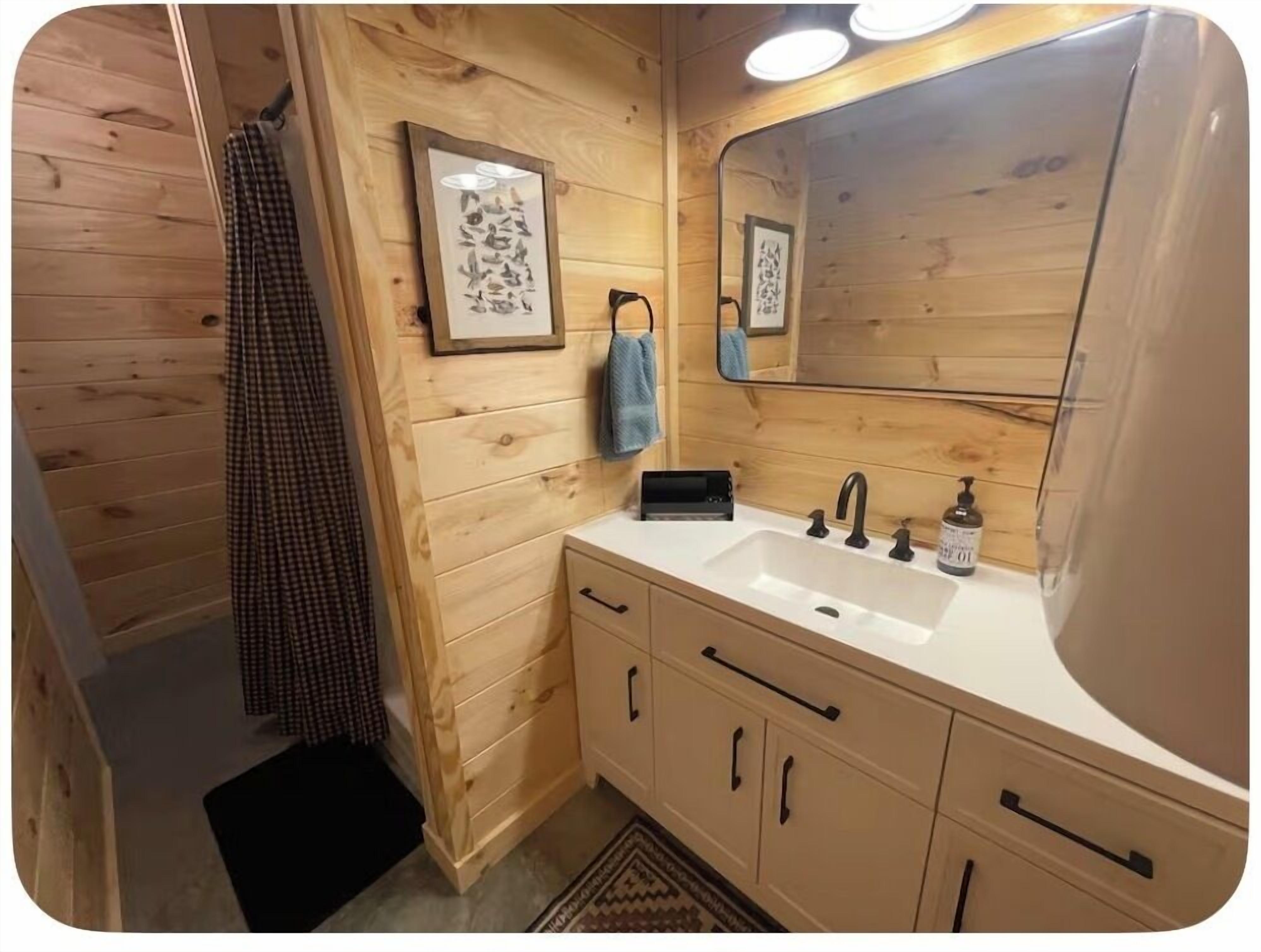 Un baño de madera con lavamanos, espejo y toallero.
