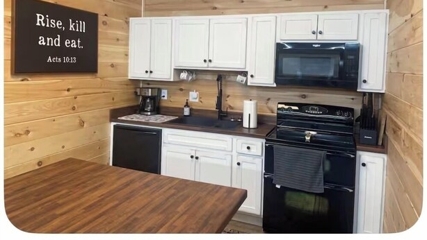 A kitchen with wooden walls, white cabinets, a black microwave, and a coffee maker. - Pole Barn Style Lodge located at Reelfoot Lake accommodating to large groups! (Hornbeak)