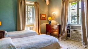 Een slaapkamer met twee bedden, een kaptafel, een lamp en een raam met gordijnen.