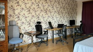 Una habitación con escritorio de madera, dos sillas, una laptop y una cama.