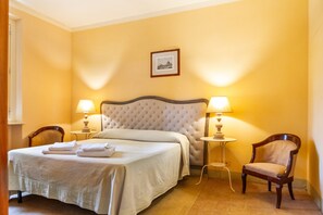 Une chambre d’hôtel avec un lit, deux lampes de chevet, une chaise et un tableau encadré au mur.
