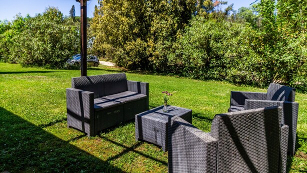 Un espacio de estar al aire libre con mobiliario de mimbre y una estructura de pérgola.